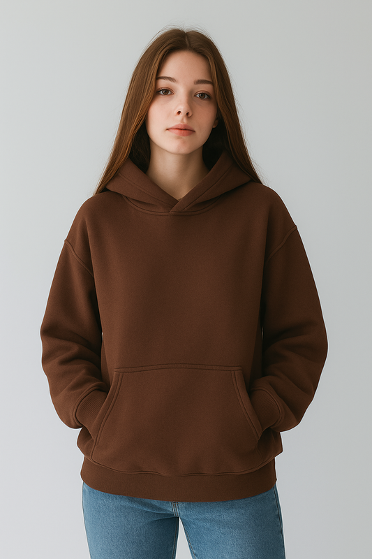 Person wearing a brown hoodie and blue jeans against a plain background