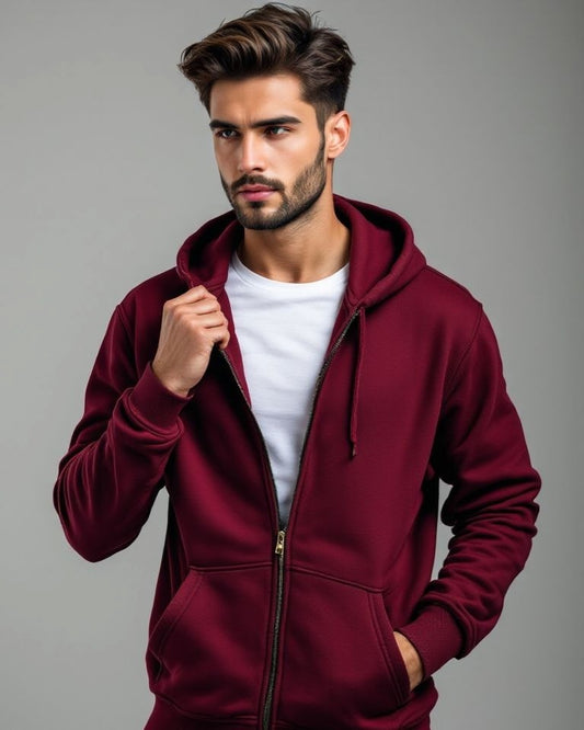 Man wearing a burgundy hoodie over a white shirt on a gray background